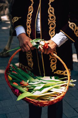 Kazak milli elbisesi içinde bir adam elinde lale sepeti tutuyor. Çimkent şehrinde Arbat caddesi boyunca yürüyün. Kazakistan'da çiçek festivali.