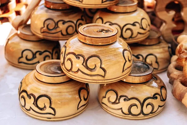 Wooden cups with the Kazakh national ornament. Utensils made of wood. Walk along Arbat street in the city of Shymkent. Festival of flowers in Kazakhstan.