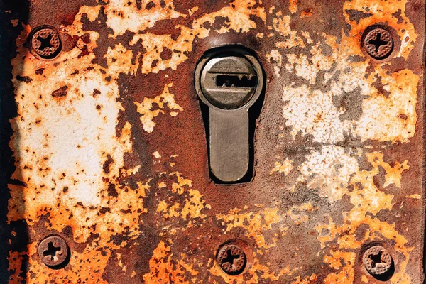 Old iron plate on the door. Corrosion on metal. Iron bolted screws. Old door lock