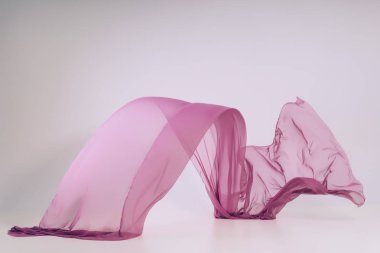 Beyaz arka plan üzerine mor kumaş. Fotoğraf stüdyosunda ultraviyole doku levitation. Yükselen bir pamuklu kumaş parçası. Açık bir arka plan üzerinde uçan renkli kumaş