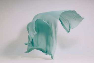 Beyaz arka planda turkuaz kumaş. Fotoğraf stüdyosunda Levitate Turkuaz kumaş. Yükselen bir pamuklu kumaş parçası. Açık bir arka plan üzerinde uçan renkli kumaş
