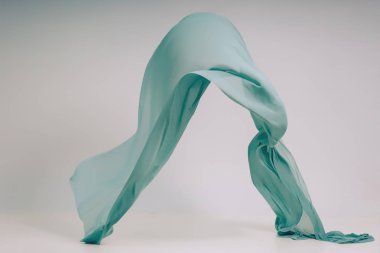 Beyaz arka planda turkuaz kumaş. Fotoğraf stüdyosunda Levitate Turkuaz kumaş. Yükselen bir pamuklu kumaş parçası. Açık bir arka plan üzerinde uçan renkli kumaş