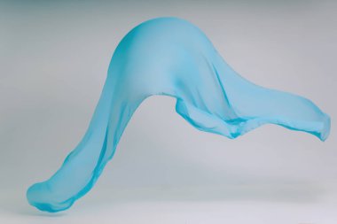 Beyaz arka plan üzerinde mavi kumaş. Fotoğraf stüdyosunda mavi kumaş levitation. Yükselen bir pamuklu kumaş parçası. Açık bir arka plan üzerinde uçan renkli kumaş