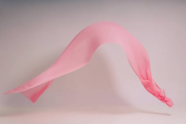 Beyaz arka planda pembe kumaş. Fotoğraf stüdyosunda pembe kumaş levitation. Yükselen bir pamuklu kumaş parçası. Açık bir arka plan üzerinde uçan renkli kumaş
