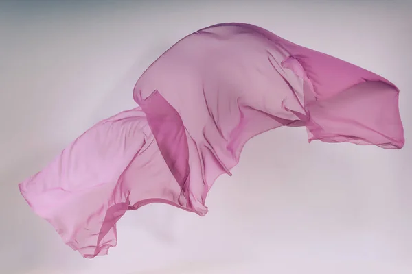 Purple fabric on a white background. Levitation of ultraviolet tissue in the photo studio. A soaring piece of cotton fabric. Flying colored fabric on a light background