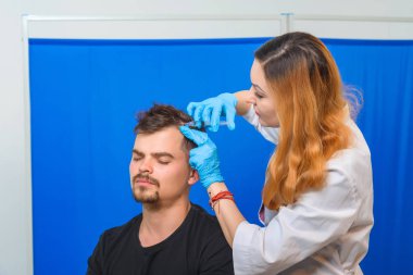 Doktorun ofisindeki kanepedeki adam. Genç bir adam için mezoterapi. Kafasına şırınga yla iğneler. Saç uzatma kel adam. Fotoğraf stüdyosundaki tıp ofisi. Vitamin enjeksiyonları