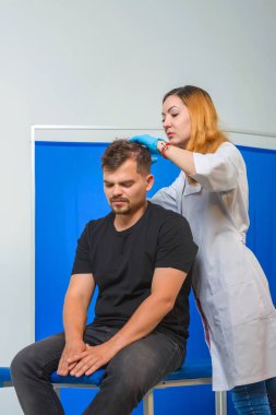 Doktorun ofisindeki kanepedeki adam. Genç bir adam için mezoterapi. Kafasına şırınga yla iğneler. Saç uzatma kel adam. Fotoğraf stüdyosundaki tıp ofisi. Vitamin enjeksiyonları