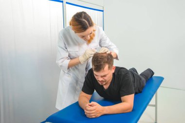 Doktorun ofisindeki kanepedeki adam. Genç bir adam için mezoterapi. Kafasına şırınga yla iğneler. Saç uzatma kel adam. Fotoğraf stüdyosundaki tıp ofisi. Vitamin enjeksiyonları