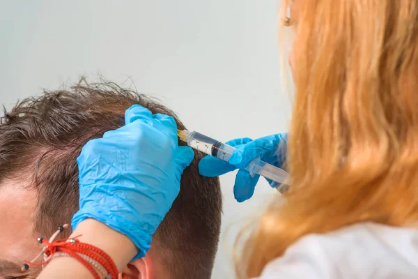 Mesotherapy of the scalp. Male pattern baldness. Bald on the man\'s head. The doctor makes a shot in the head of a man.