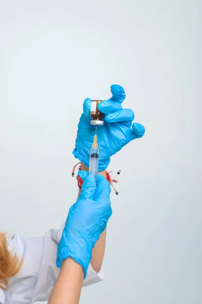 Woman doctor fills syringe with medicine. Procedures in the medical office. Nurse's hands in blue latex gloves.