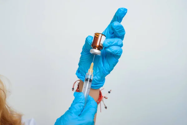 Woman doctor fills syringe with medicine. Procedures in the medical office. Nurse\'s hands in blue latex gloves.