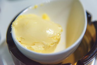 Beyaz bir bardakta tereyağı. Kahvaltıda sarı tereyağı. Ekmek üzerine yaymak için çözülmüş tereyağı