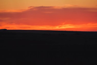 Bozkırın üzerinde turuncu gün batımı. Kazakistan'da doğaya akşam manzarası. Gökyüzünde gün batımı.
