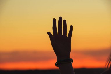 Turuncu gün batımına karşı kızın eli. Kazakistan'da açık hava rekreasyon. Gökyüzünde turuncu gün batımı.