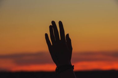 Turuncu gün batımına karşı kızın eli. Kazakistan'da açık hava rekreasyon. Gökyüzünde turuncu gün batımı.