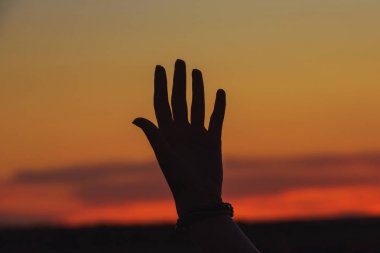 Turuncu gün batımına karşı kızın eli. Kazakistan'da açık hava rekreasyon. Gökyüzünde turuncu gün batımı.