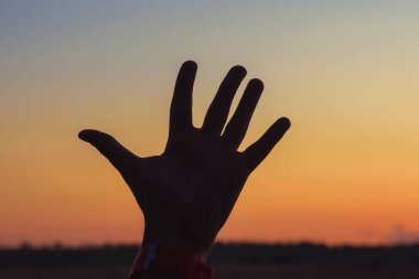 Turuncu bir gün batımının arka planındaki el ele adam. Kazakistan'da açık hava rekreasyon. Gökyüzünde turuncu gün batımı.