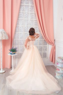 Pembe arka plan perdeler üzerinde bej gelinlik kız. Düğün fotoğraf çekimi. Muhteşem bir elbiseli gelin.
