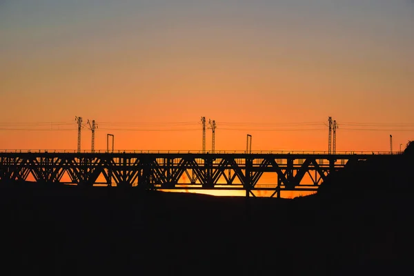 哈萨克斯坦的铁路桥 橙色日落背景的货运列车 中亚铁路货物运输 桥结构 — 图库照片