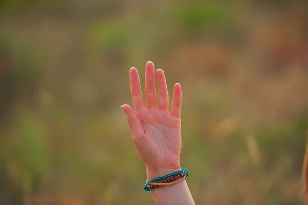 緑の草原を背景に少女の手 カザフスタンのアウトドアレクリエーション 女の子の手に木製のビーズで作られたブレスレット — ストック写真