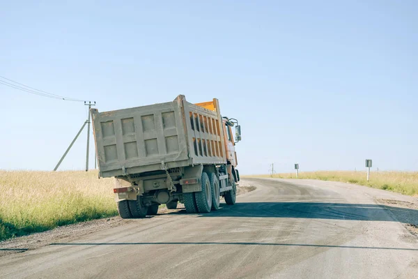 Dump truck with gravel on the road. Dump trucks make a mound of gravel stones at the roadside. A large construction truck