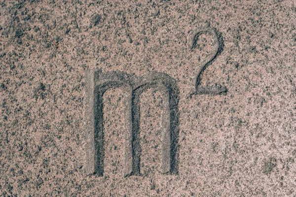 Sign M carved on the stone. Letter of the alphabet on granite. Stone engraving