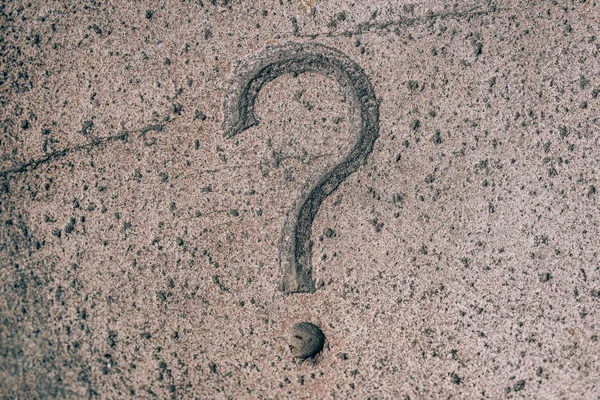 Question mark carved on a stone. Punctuation mark on granite. Stone engraving