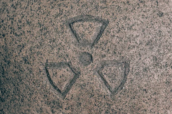 Nuclear sign carved on the stone. Symbol of danger on granite. Stone engraving
