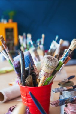 Atölyenin arka planında bir kavanozda yakın plan fırçalar. Ahşap saplı sanatsal fırça. Mobilya ve dekorları tebeşirle boyamak için atölyedeki masaüstü.