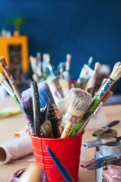 Atölyenin arka planında bir kavanozda yakın plan fırçalar. Ahşap saplı sanatsal fırça. Mobilya ve dekorları tebeşirle boyamak için atölyedeki masaüstü.