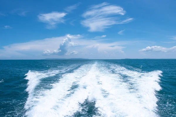 Sürat teknesi mavi gökyüzü ile arkasında su yüzeyinde iz