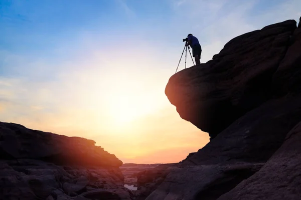 Fotoğrafçı gün doğumu sabahı zirvede durmak ve fotoğraf çekmek 