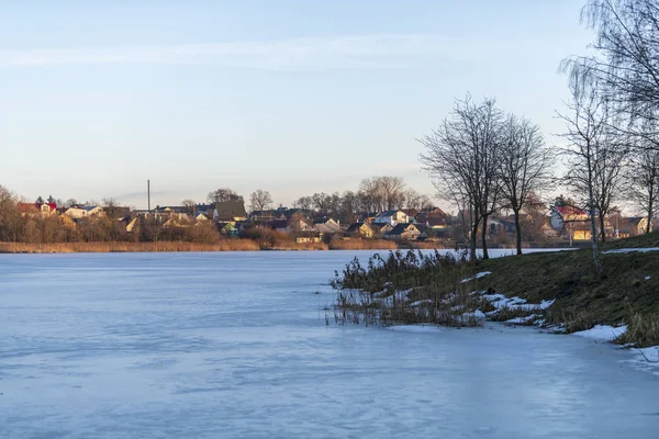 Árbol desnudo inclínese sobre el agua, refleje. Las ramas de los árboles se inclinaron sobre el lago en un hermoso día de invierno. Cielo azul sobre fondo. Témpano de hielo, nieve flotando en el agua. Un día soleado brillante. Calma y tranquilidad . —  Fotos de Stock