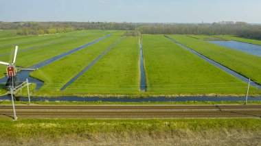 Bir dike, kanallar ile Hollanda kırsal kırsal eski bir Hollanda geleneksel yel değirmeni havadan görünümü. Tren. köprü ve yol.