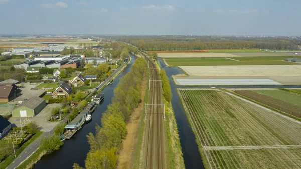 Vista aérea del pueblo holandés, canales, carretera ferroviaria y campos de bulbos de tulipán — Foto de Stock