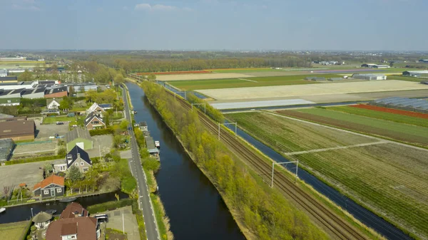 Vista aérea del pueblo holandés, canales, carretera ferroviaria y campos de bulbos de tulipán —  Fotos de Stock