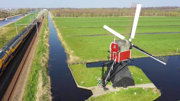 Aerial view of high speed train passing by traditional Dutch windmill, Netherlands, Holland — Stock Video