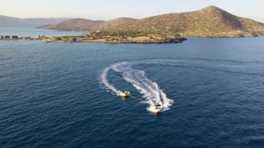 Motorlu bir teknenin tüpü çektiği hava görüntüsü. Elounda, Girit, Yunanistan