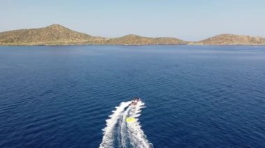 Motorlu bir teknenin tüpü çektiği hava görüntüsü. Elounda, Girit, Yunanistan