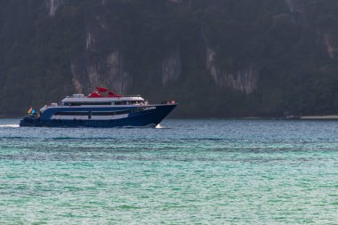 Yolcu feribotu, Tayland kıyıları yakınlarındaki turkuaz tropikal sularda yol alıyor. Turistleri taşıyan büyük bir gemi. Mavi okyanus, yaz tatili ve deniz macerası konsepti..