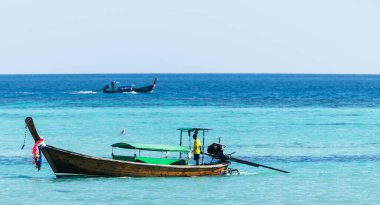 Tayland adası kıyısı yakınlarındaki turkuaz tropikal denizde geleneksel uzun kuyruklu tekne. Egzotik suyla okyanus manzarası, yaz tatili, deniz kültürü ve macera gezisi. Turizm, tatil ve doğa konsepti için mükemmel deniz manzarası.