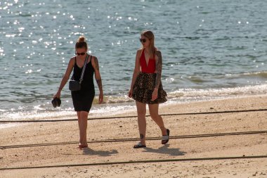 Ko Phi Phi, Tayland - Turistler güneşli bir günde sahilde yalınayak yürürler. Sahne, Phi Phi Adası 'ndaki sahil kenarında gelişigüzel yaz modası, dövmeler ve eğlence aktivitelerini gösteriyor..