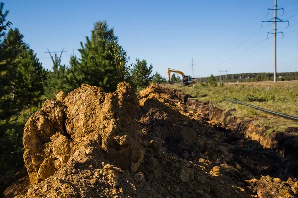 ekskavatör uzakta durur ve bir siper kazır gibi toprak clods üzerinden bakmak