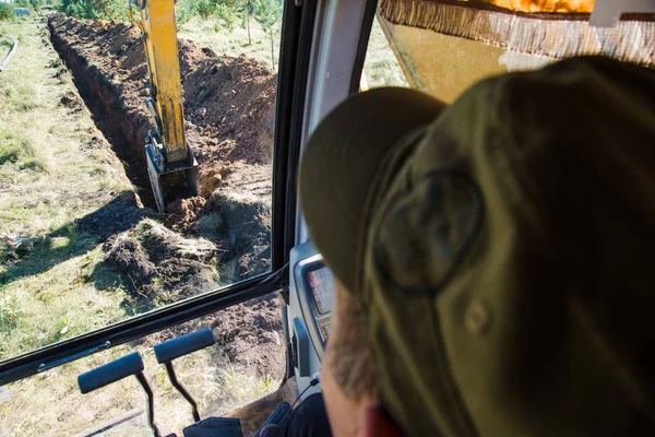 excavator digging a trench. view from driver\'s cabin