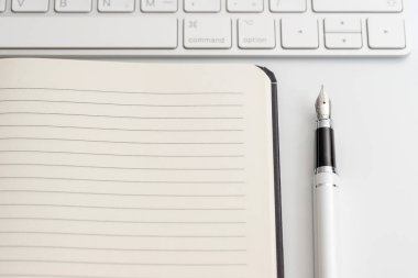 Not defteri, klavye ve dolma kalem ile beyaz tablo. Yukarıdan görüntülemek