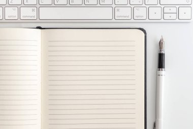 Not defteri, klavye ve dolma kalem ile beyaz tablo. Yukarıdan görüntülemek