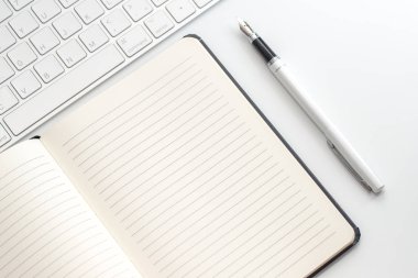 Not defteri, klavye ve dolma kalem ile beyaz tablo. Yukarıdan görüntülemek