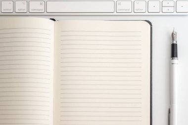 Not defteri, klavye ve dolma kalem ile beyaz tablo. Yukarıdan görüntülemek