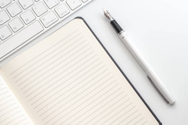 Not defteri, klavye ve dolma kalem ile beyaz tablo. Yukarıdan görüntülemek