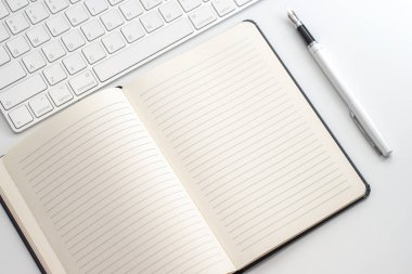 Not defteri, klavye ve dolma kalem ile beyaz tablo. Yukarıdan görüntülemek